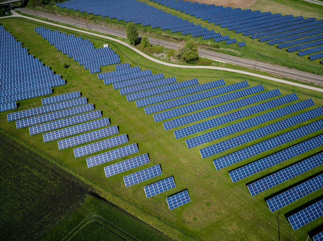 Aerial view of a grass field with blue solar panels (illustrative image)