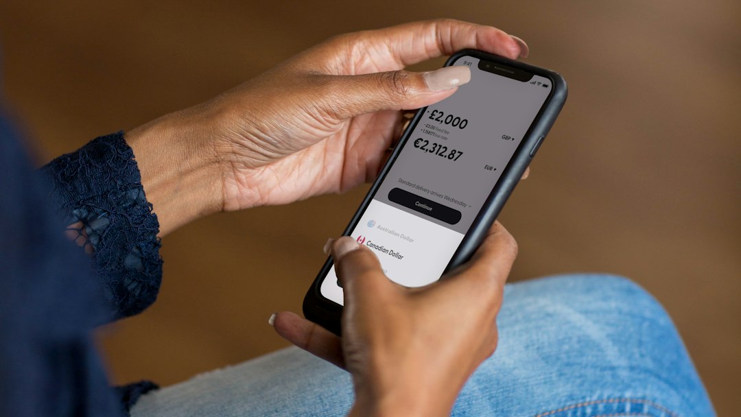Hands holding a smartphone using a banking app to transfer money (illustrative image)