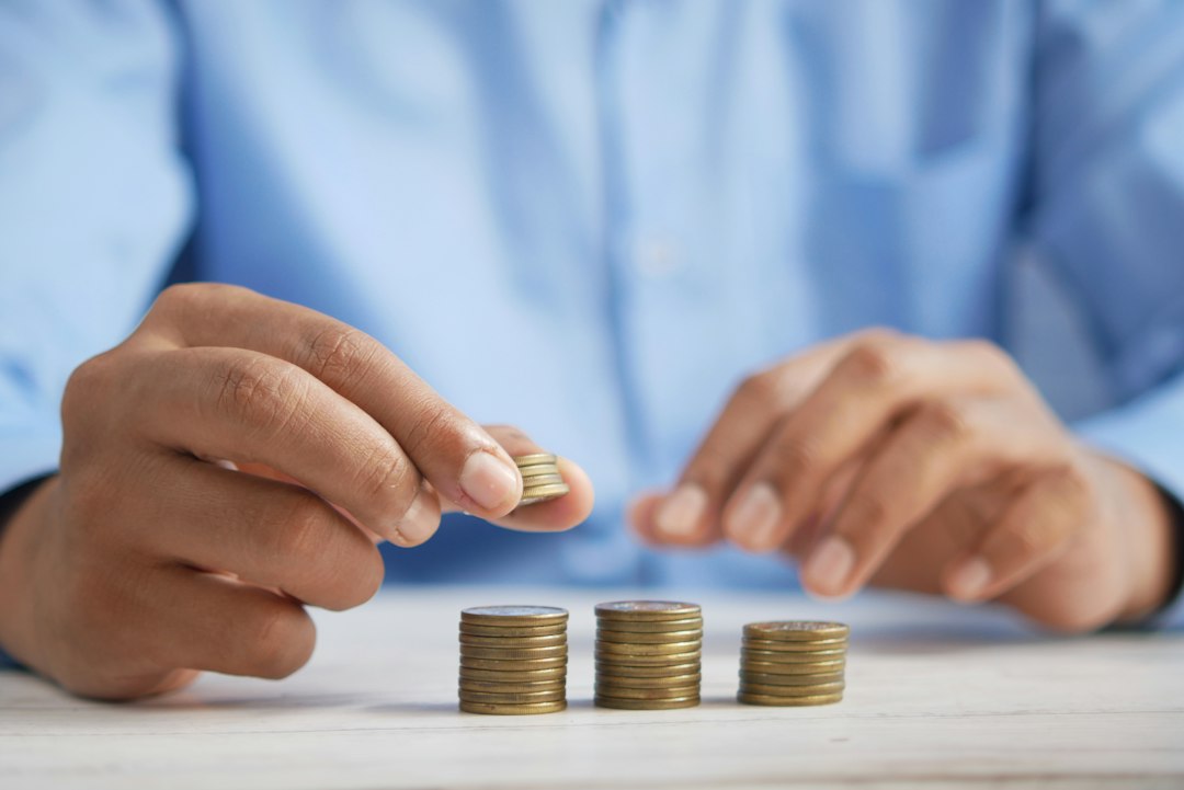 Person stacking coins on a table (illustrative image)
