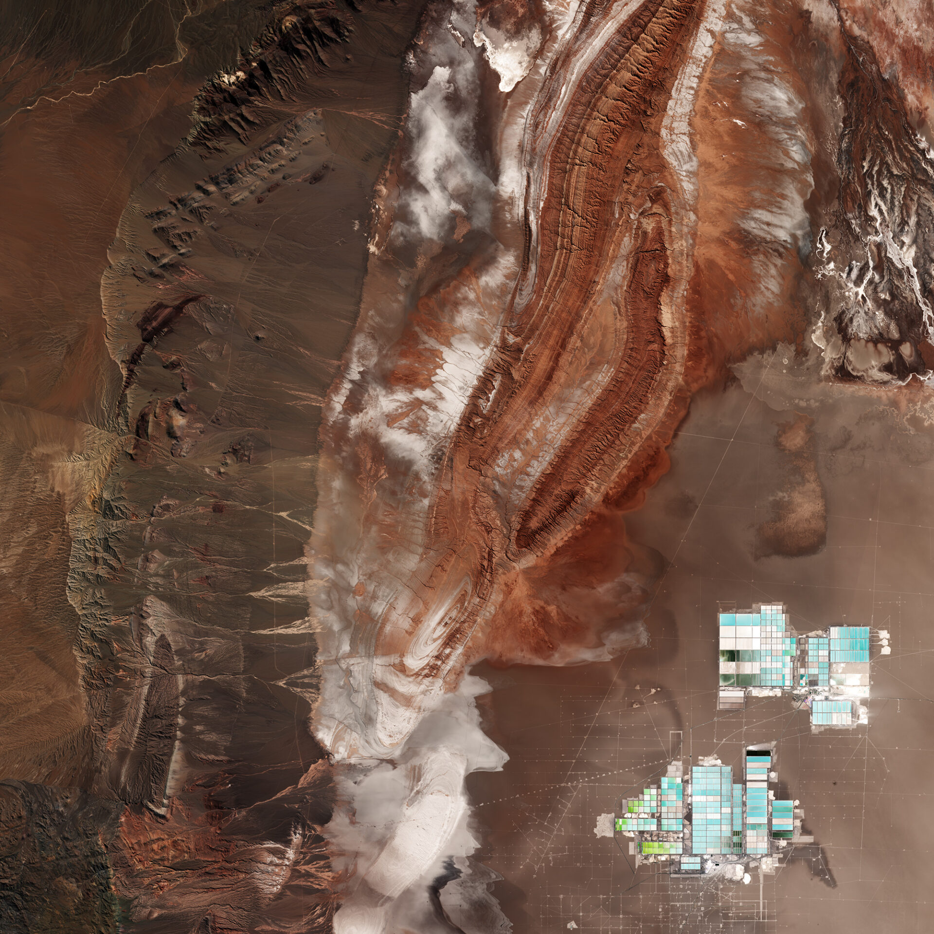 Satellite imagery of the Salar de Atacama in Chile showcasing the geometric layout of vast lithium evaporation ponds in the Atacama Desert.